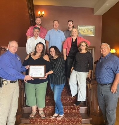 Nichole Griffith and Lacey Bateman from Victim-Witness Assistance Services and the MBCC Board of Directors on the staircase at the Grant Union Hotel in Fort Benton